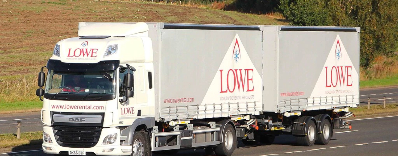 White truck with "LOWE" logo and red lettering, parked against a grassy background.