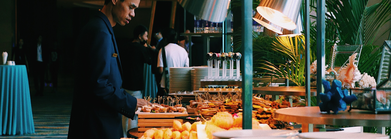 A man inspects a selection of pastries and hors d'oeuvres at a culinary event.