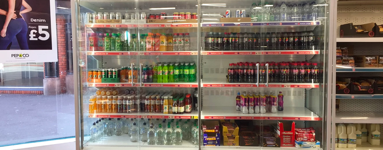 Shelves filled with various beverages, including green bottles, soft drinks, and juices.