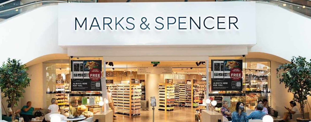 Marks & Spencer store entrance featuring bright lighting and organised shelving displays.