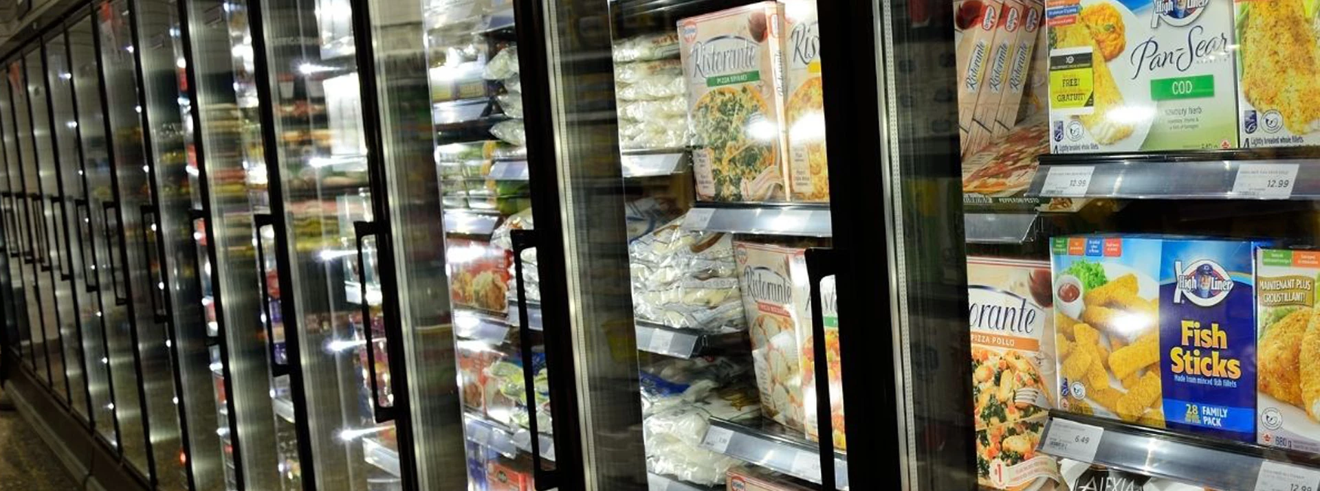 Frozen food display featuring various packaged meals in colourful boxes, set against a metallic background.