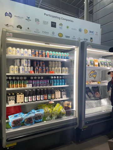 Chilled beverage display featuring colourful bottles and packaged products, with a person observing on the right.