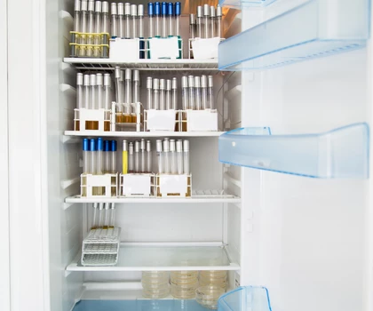 Organised refrigerator shelves displaying various pharmaceutical vials and syringes in a clean, white interior.