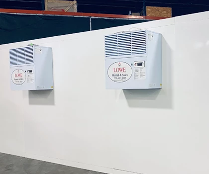 Two white cooling units mounted on a plain wall in a modular cold room setting.