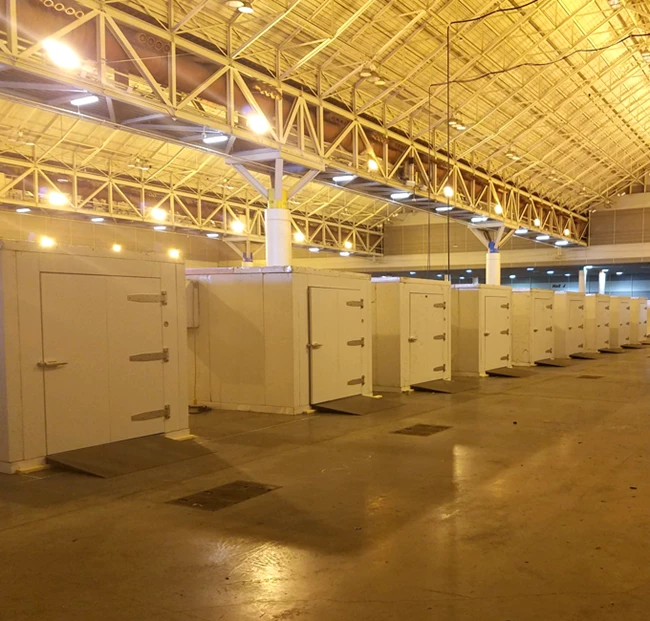 Modular white cold rooms arranged in a spacious industrial setting with a high ceiling.
