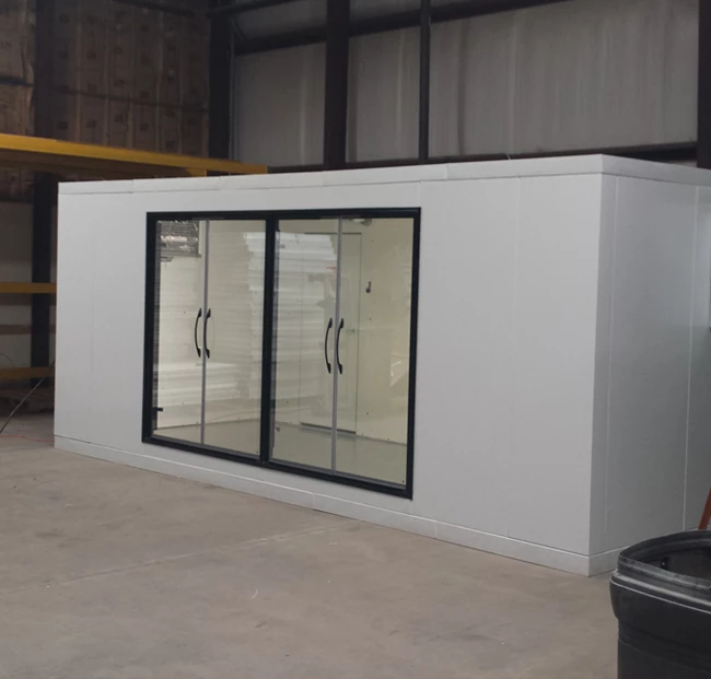 Modular walk-in cold room with glass double doors, featuring a white exterior and industrial background.