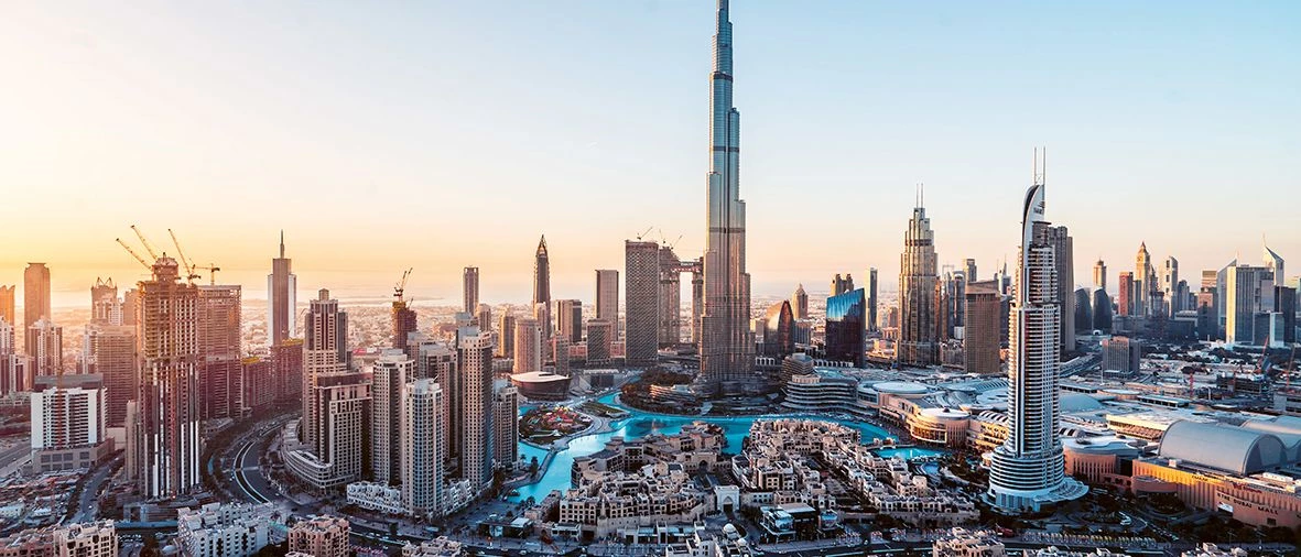 Skyline featuring the Burj Khalifa, surrounded by modern buildings and a soft sunset glow.