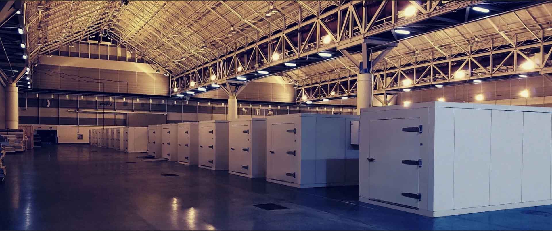 Interior of a cold room featuring several white storage units under warm overhead lighting.