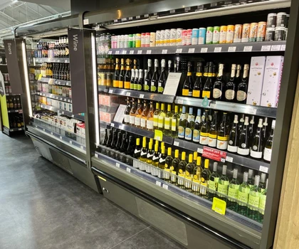 A well-stocked beverage fridge displaying various bottles of wine and spirits in vibrant colours.