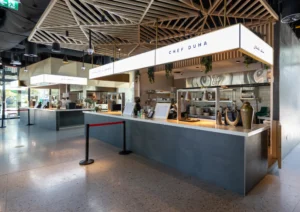 Modern food stall with a grey counter, wooden ceiling, and signage displaying "Food Zone.