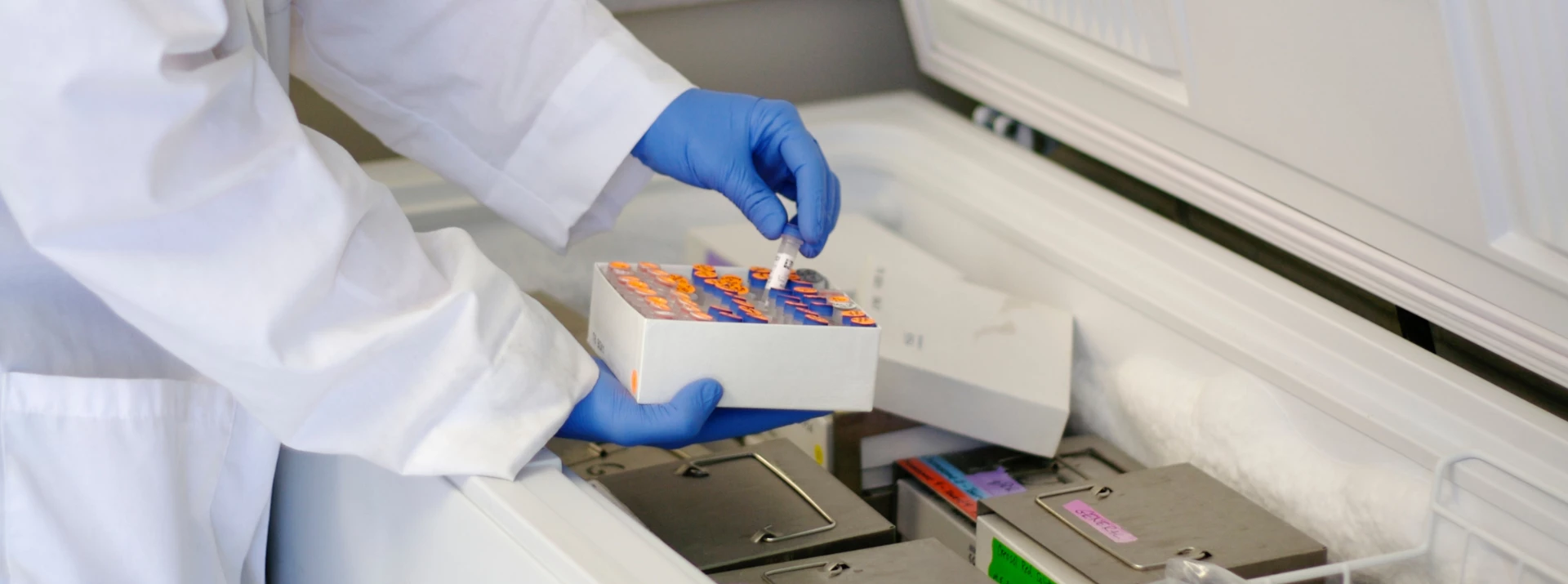 A gloved hand holds a colourful box above laboratory equipment, suggesting a scientific process.