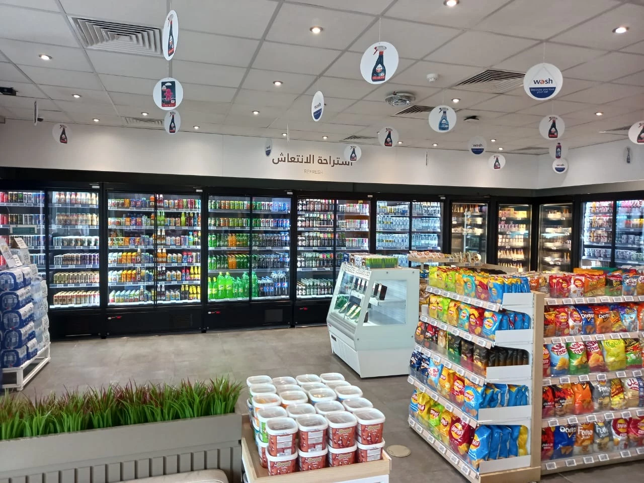 Brightly lit grocery store interior featuring colourful shelves of snacks and frozen food displays.