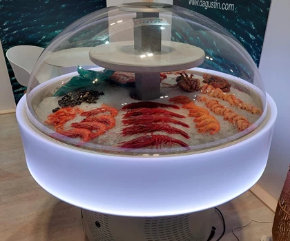 A display featuring various seafood, including vibrant red and orange fish, under a transparent dome.
