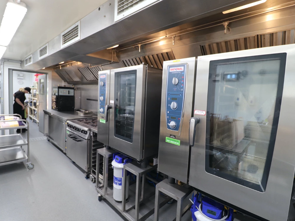 Modern stainless steel kitchen equipment, including ovens and stoves, in a clean, well-lit space.