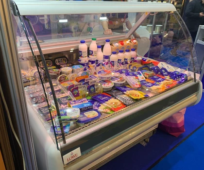 Chilled display cabinet filled with various dairy products, including milk bottles and cheese packets.