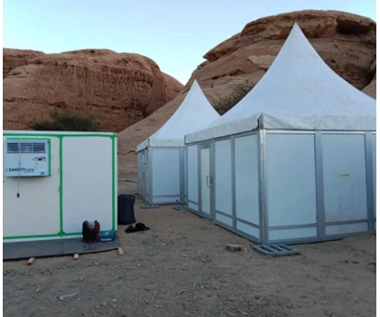 White tents and a glass-fronted structure set against rocky terrain in a desert environment.