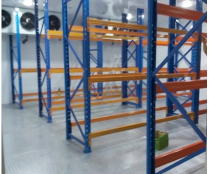 Empty metal shelving units in blue and orange, set against a clean, grey floor.