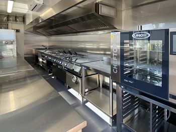 Modern temporary kitchen with stainless steel surfaces and equipment, featuring a glass-fronted oven.