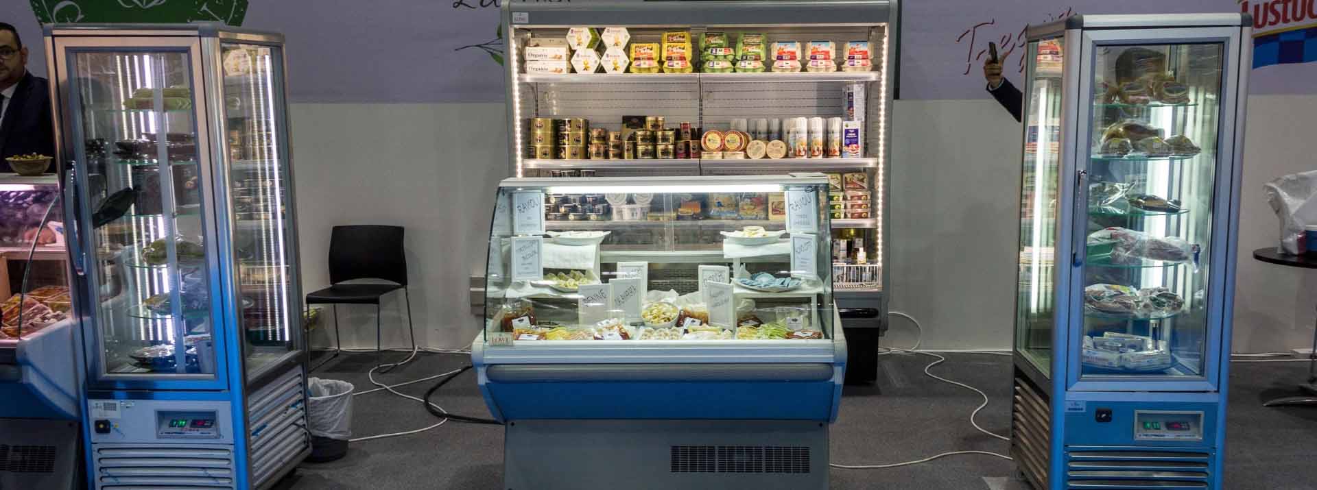 A glass-fronted display case filled with assorted ice creams and frozen treats, set against shelves of packaged goods.