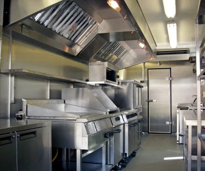 Modern stainless steel kitchen interior with cooking equipment and ventilation system.