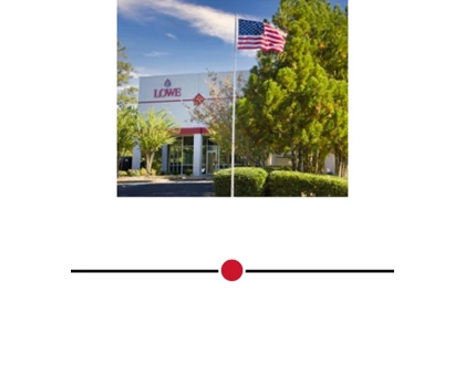 American flag waving in front of a modern building surrounded by green trees and blue sky.