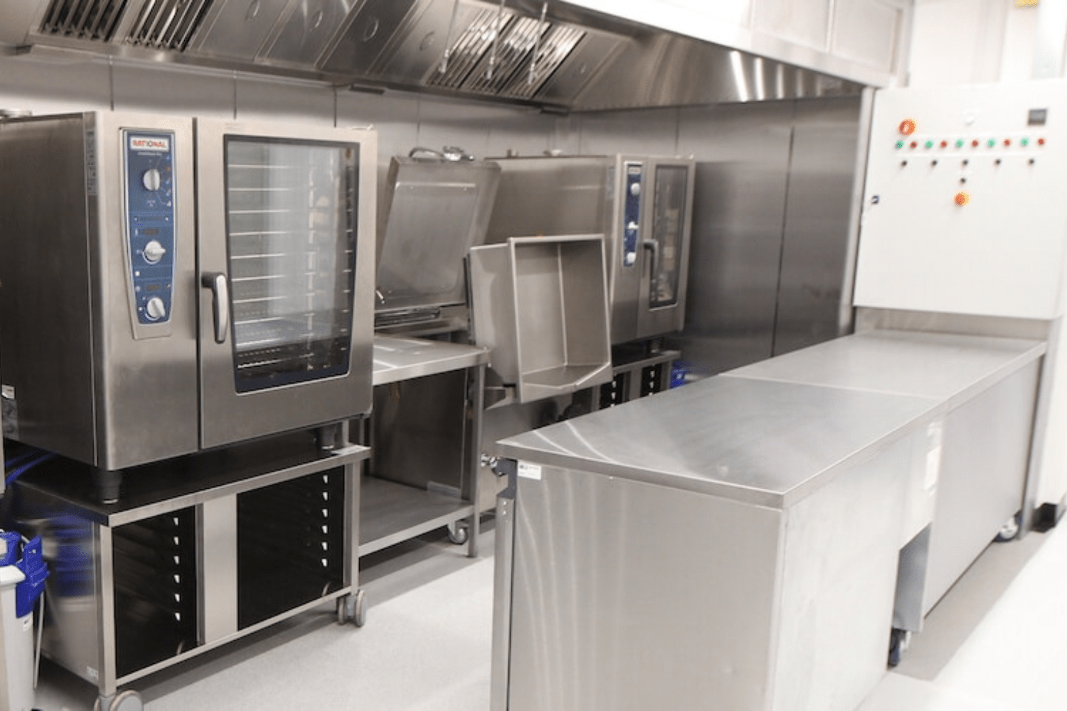 Stainless steel catering equipment in a modern kitchen, featuring ovens and a cold storage unit.