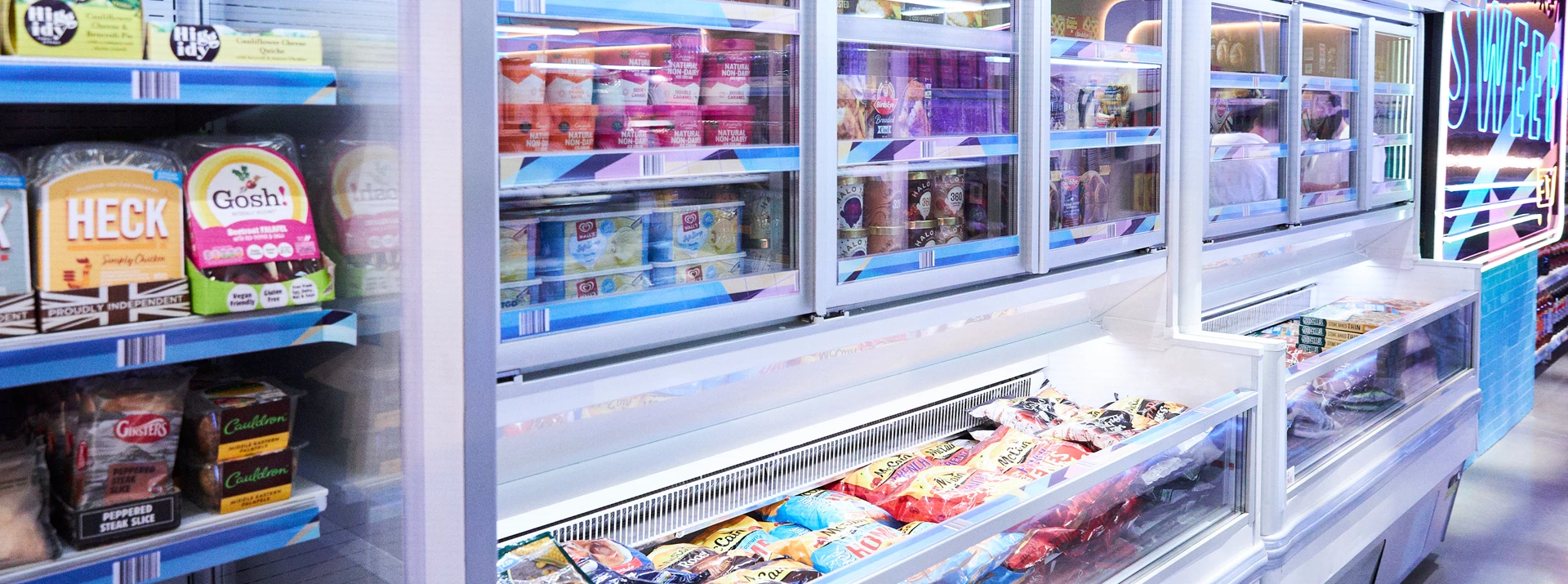 Frozen food section displaying colourful ice cream tubs and bags of frozen snacks in clear cases.