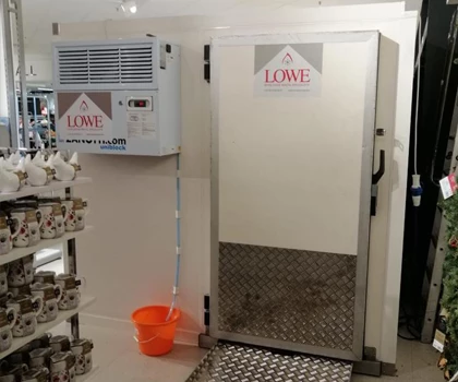 Metallic door with warning signs, adjacent to an air conditioning unit and an orange bucket.