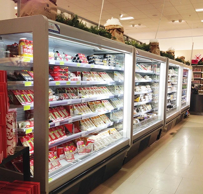 Chilled supermarket aisle displaying various packaged frozen foods in bright, illuminated freezers.
