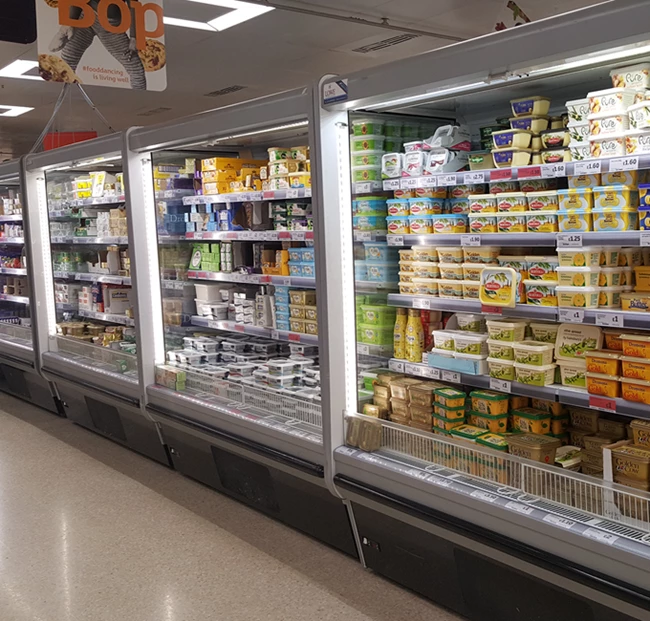Chilled supermarket aisle displaying various dairy products in colourful packaging.