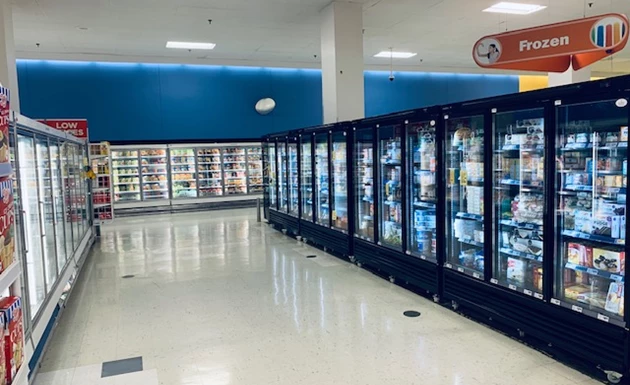 Row of glass-fronted freezers against a blue wall, showcasing various frozen products.