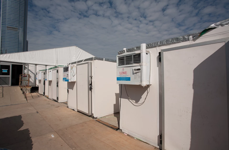 Row of white storage units with grey roofs under a partly cloudy sky.