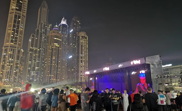 Crowd gathered at night for Red Fest, with illuminated skyscrapers and a vibrant stage backdrop.