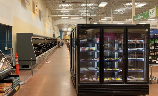 A black refrigerated display case filled with products in a spacious, well-lit retail environment.