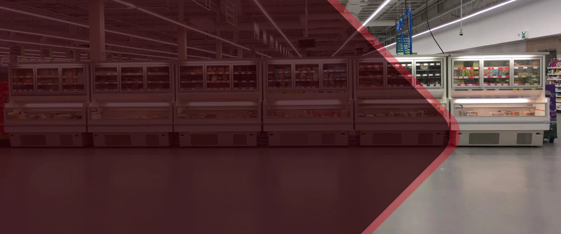 Display of refrigerated units with glass doors, set against a dark red floor and ceiling.