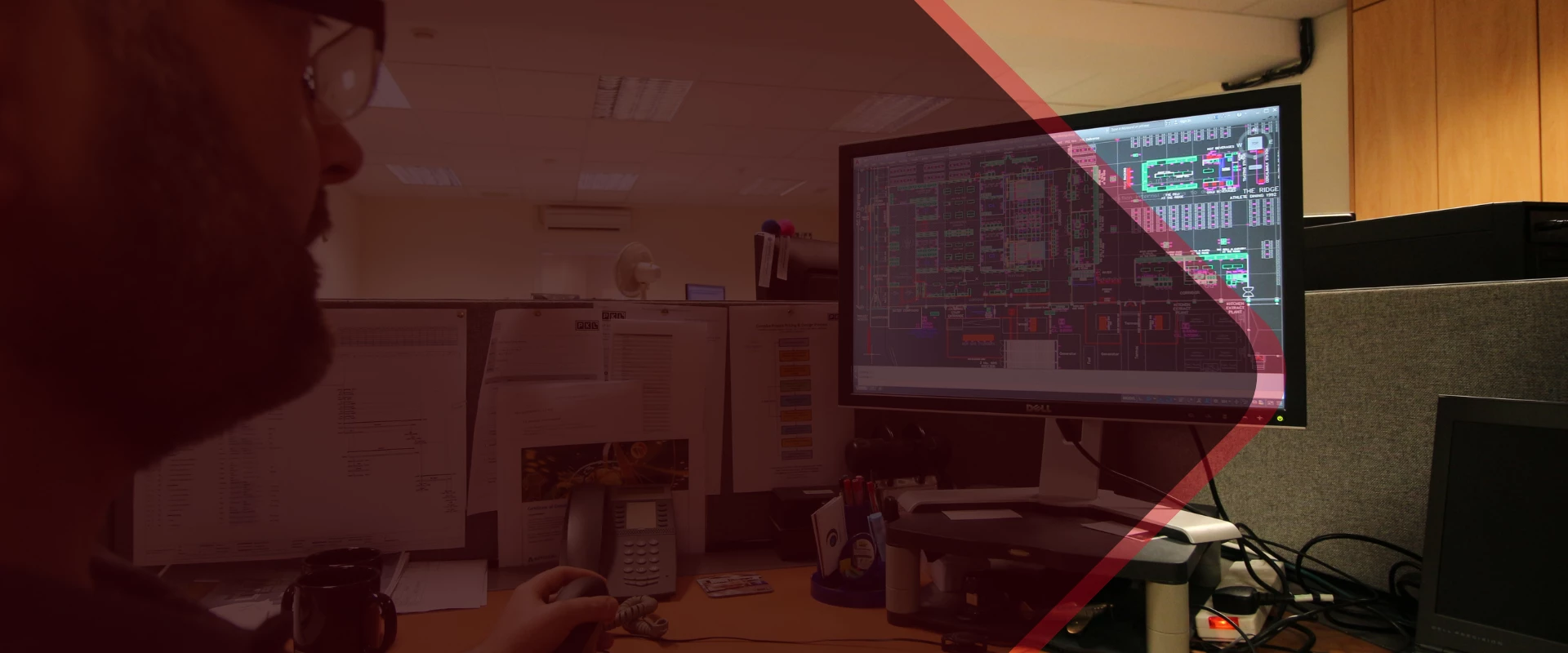 A hand reaches towards a computer monitor displaying data, with a blurred office background.