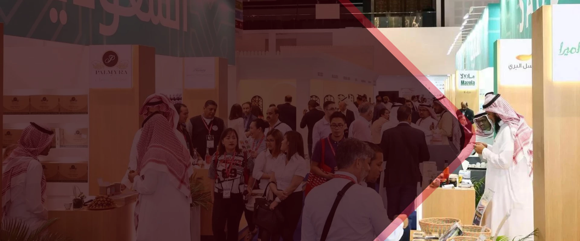 Crowd of attendees in white and patterned clothing at an exhibition, engaged in conversation.