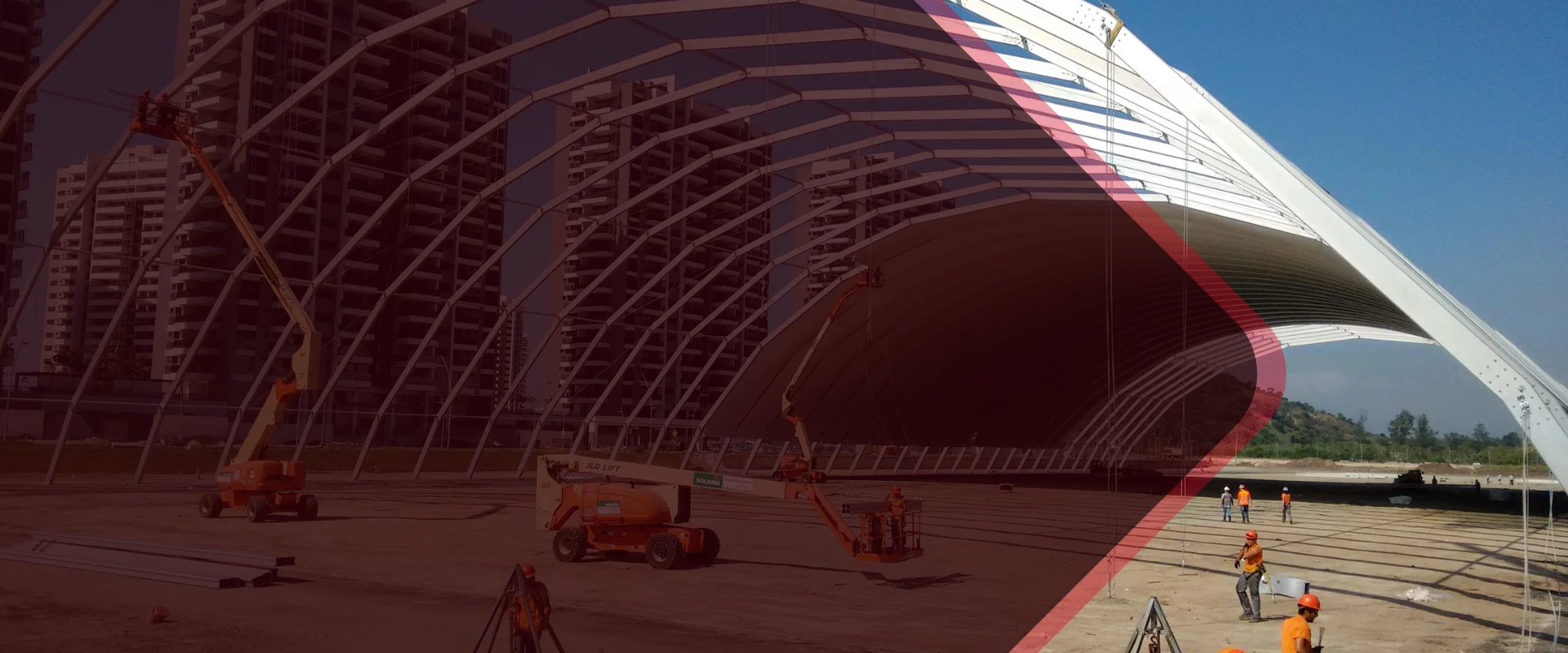 Construction site featuring a large steel structure with cranes and machinery in the foreground.