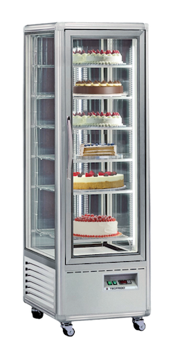 A glass display fridge showcasing various cakes, featuring white, chocolate, and red decorations.