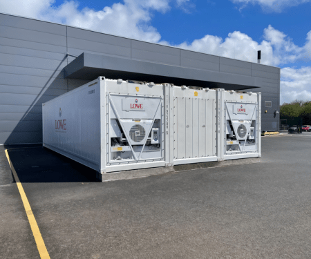 White containerised 2 bay cold storage unit with visible air conditioning units, set against a grey building.