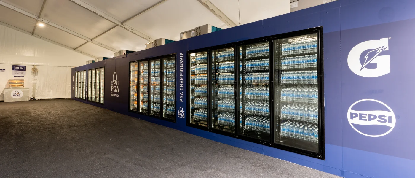 A large display of glass-fronted refrigerators filled with bottled water, set against a blue background.