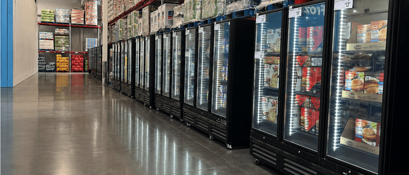 Rows of black glass-fronted freezers filled with various frozen food products in a store aisle.