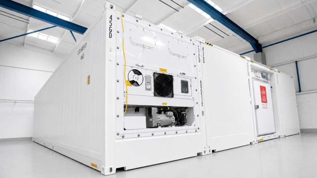 White cold storage container with visible machinery and control panel, set against a bright interior.