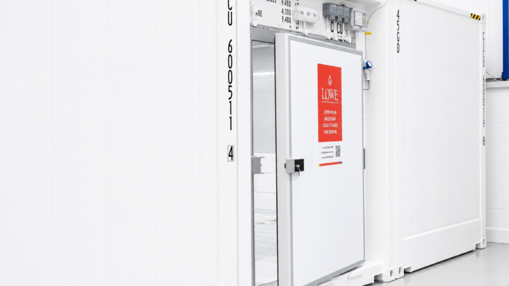 White cold storage unit with a red warning sign, featuring a metal door and visible controls.