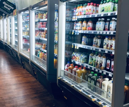 Refrigerated display units filled with various colourful beverages in a grocery store aisle.