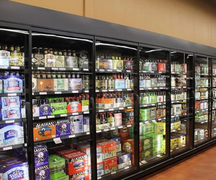 Refrigerated display case filled with various beverages, featuring colourful packaging and glass doors.