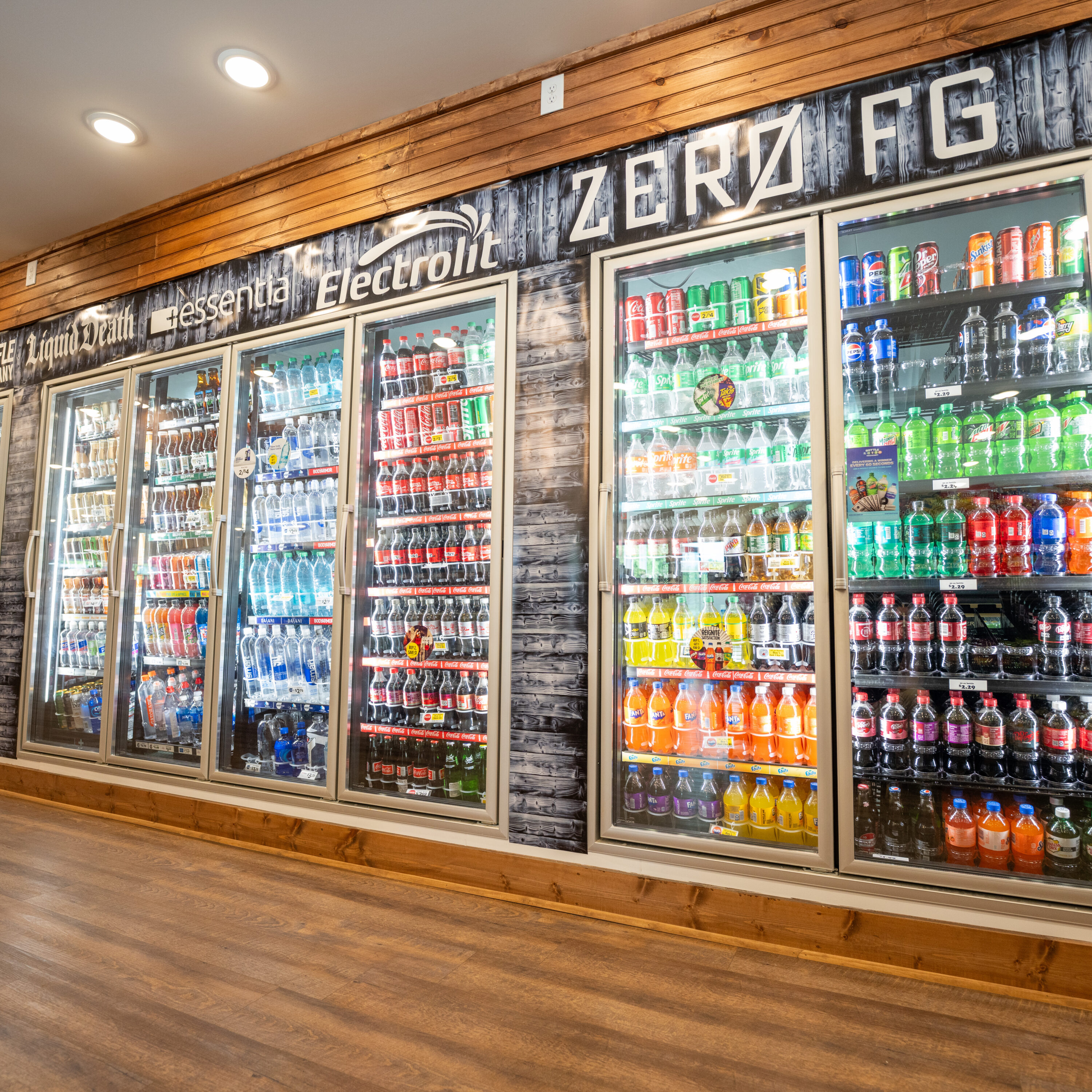 Refrigeration display showcasing various brightly coloured beverages against a wooden wall backdrop.