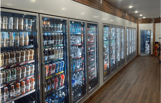 Rows of glass-fronted vending machines filled with colourful drinks against a wooden wall.