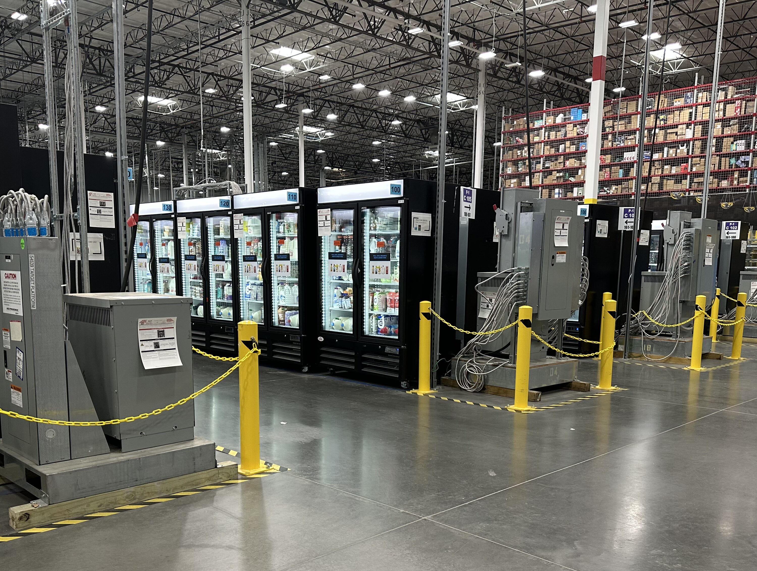 Refrigeration units in a spacious warehouse, featuring grey floors and yellow safety barriers.