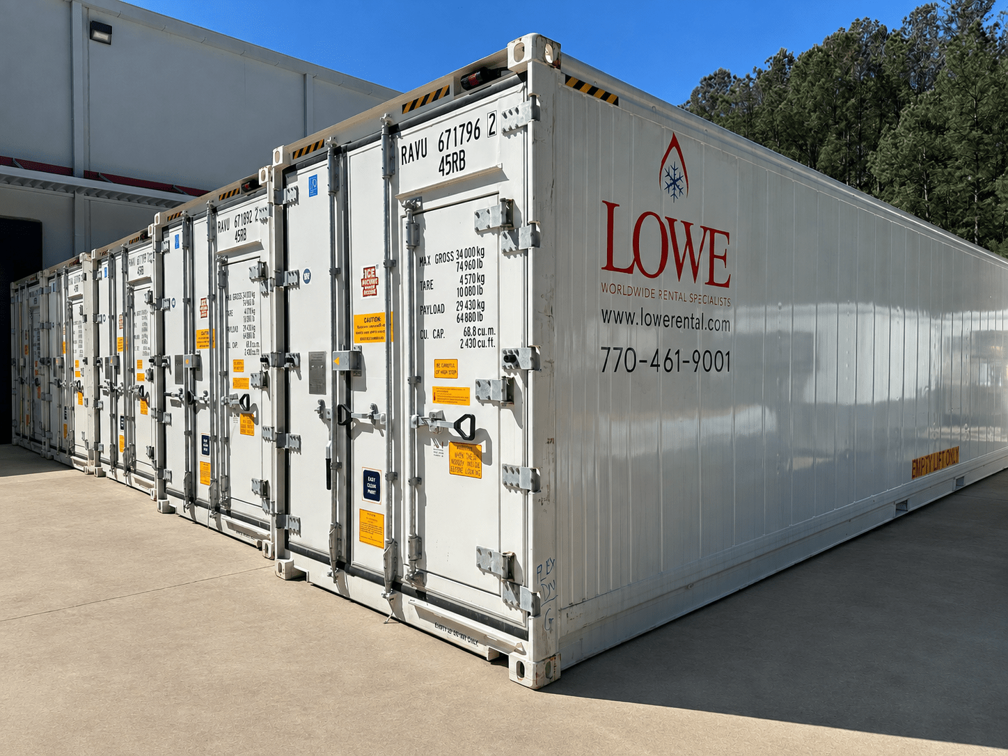 White shipping containers with yellow labels and Lowe branding, positioned on a concrete surface.
